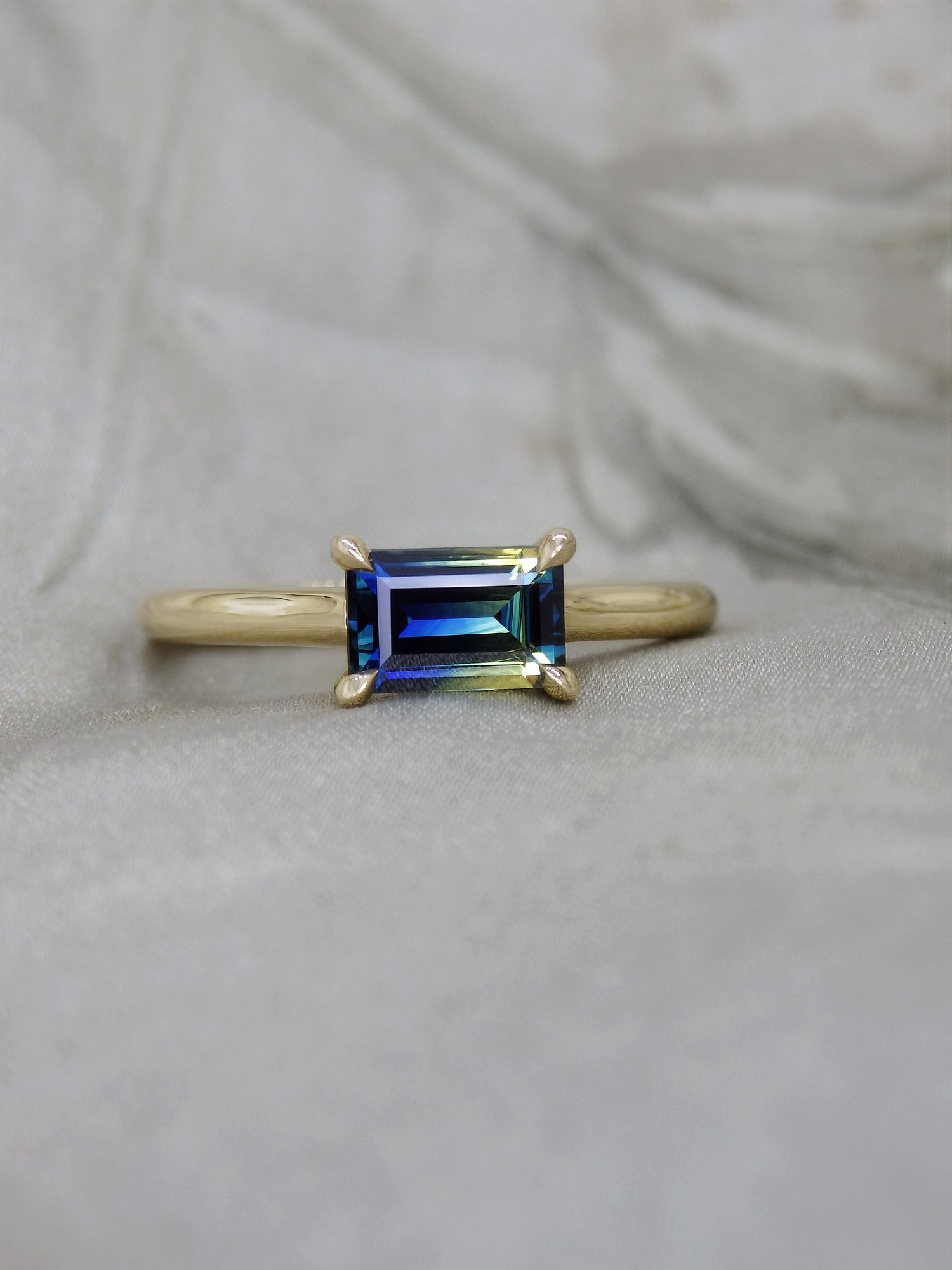 Split bi-colour blue and yellow Australian baguette cut Parti Sapphire in an east-west across the finger four claw 18k yellow gold solitaire engagement ring 