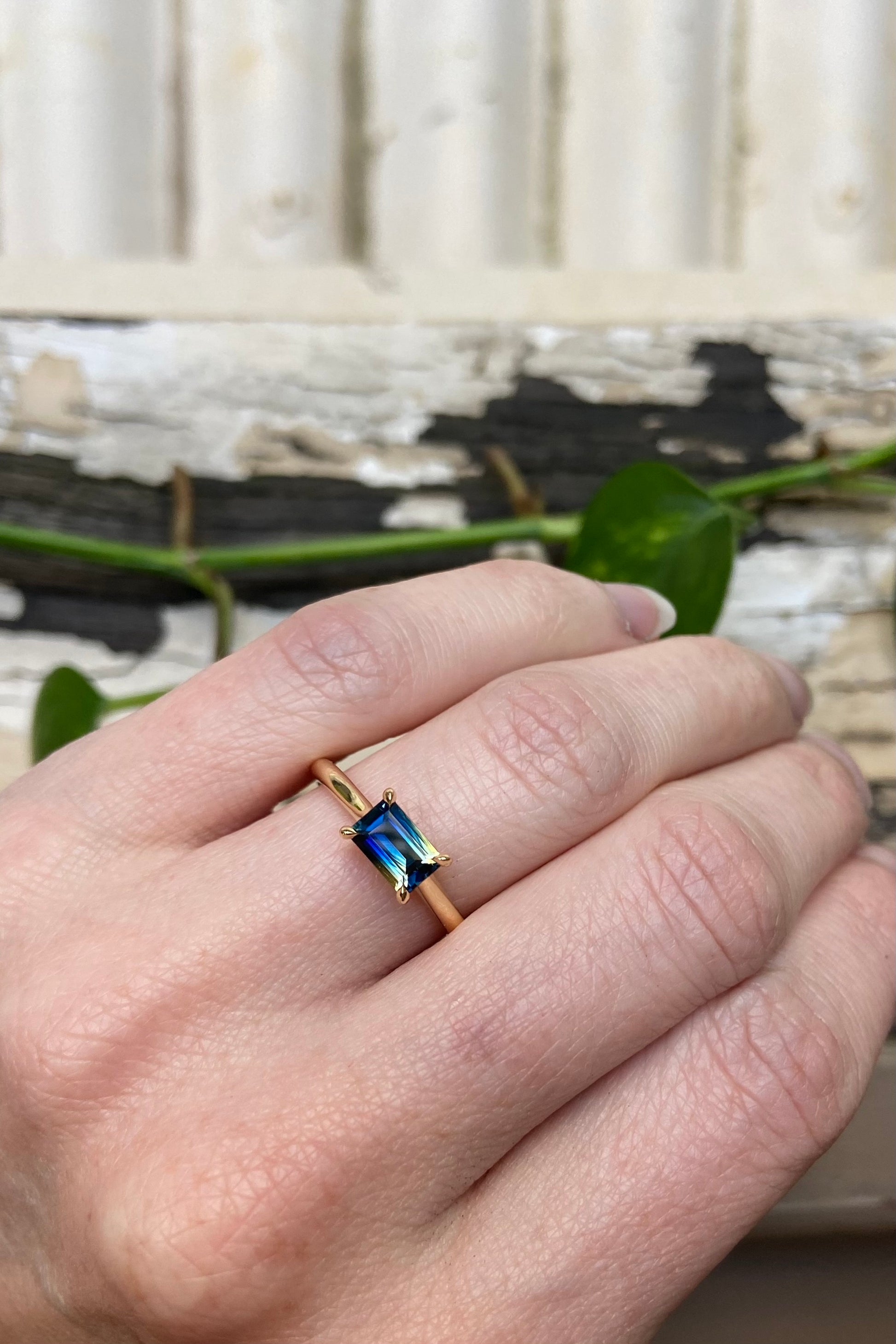 Split bi-colour blue and yellow Australian baguette cut Parti Sapphire in an east-west across the finger four claw 18k yellow gold solitaire engagement ring on the hand on the finger