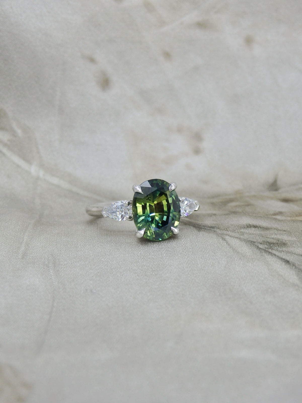 Big oval teal parti sapphire trilogy engagement ring with natural pear shape diamond side stones handmade in platinum