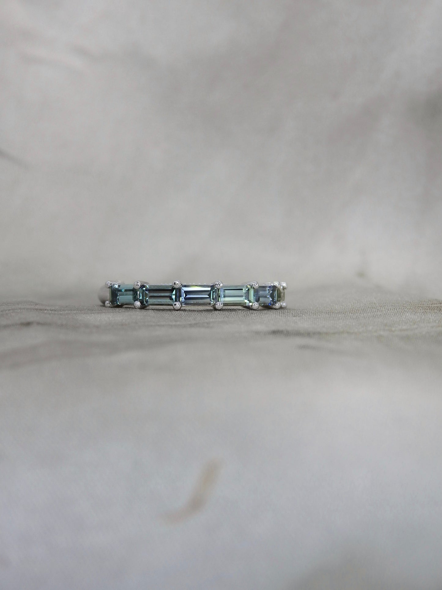 blue and teal baguette cut sapphires held in by shared platinum claws for a wedding ring or celebration ring 