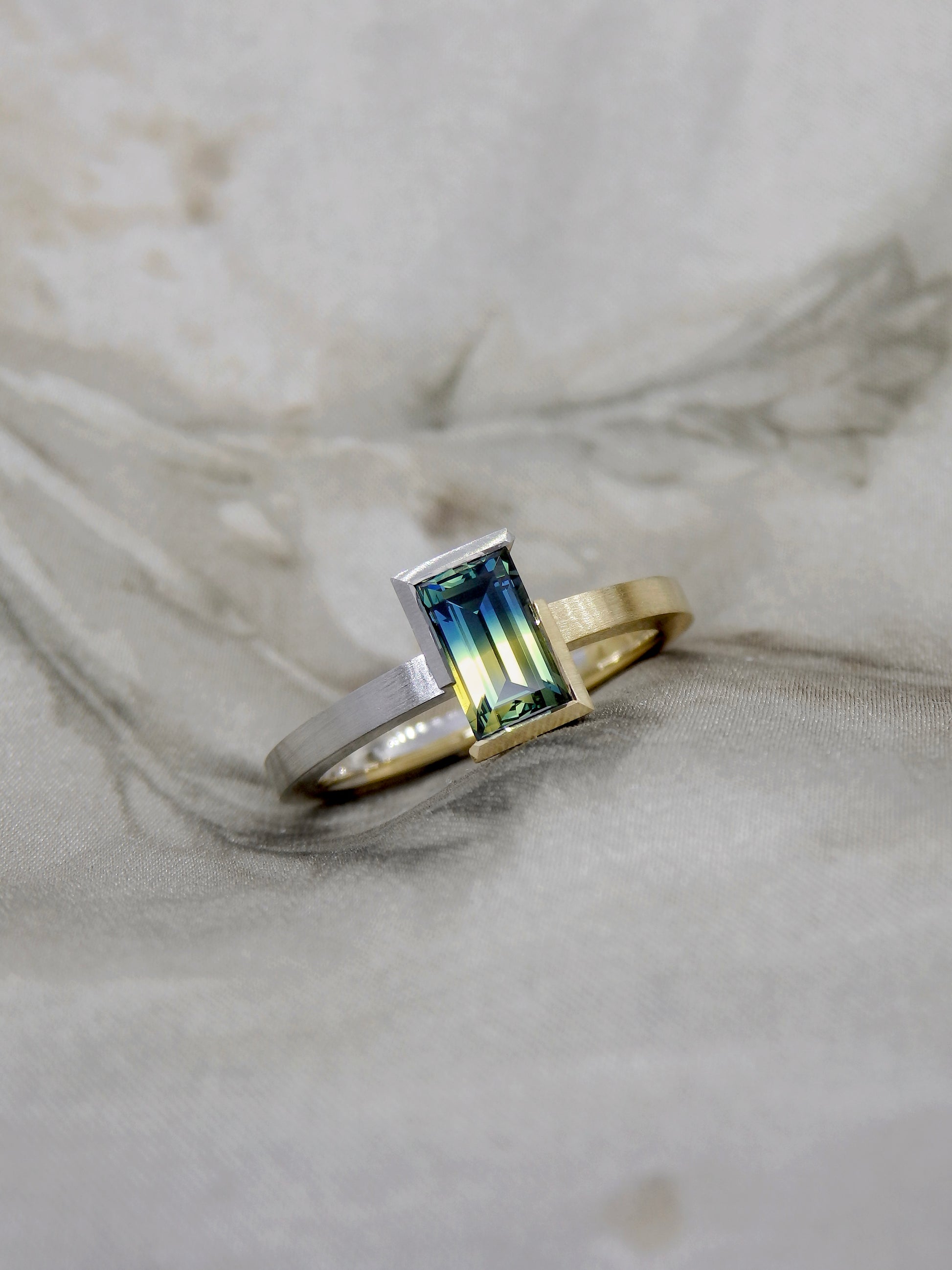 Bi colour baguette cut blue and yellow split Australian parti sapphire in two tone 18k yellow gold and platinum partial bezel solitaire engagement ring. Brushed matte finish