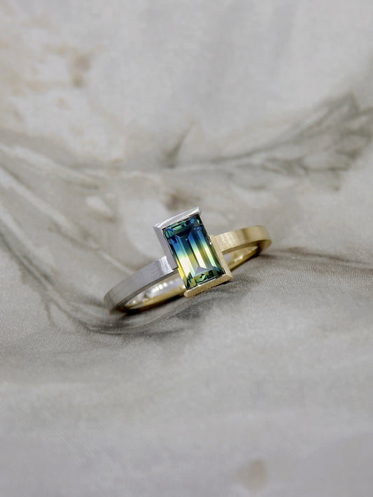 Bi colour baguette cut blue and yellow split Australian parti sapphire in two tone 18k yellow gold and platinum partial bezel solitaire engagement ring. Brushed matte finish