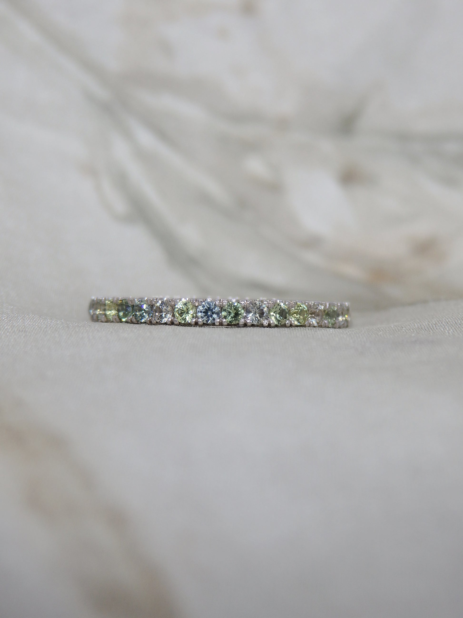 Multi tone pastel green, blue, yellow and white sapphires micro-pave set in 18ct white gold wedding band or eternity ring