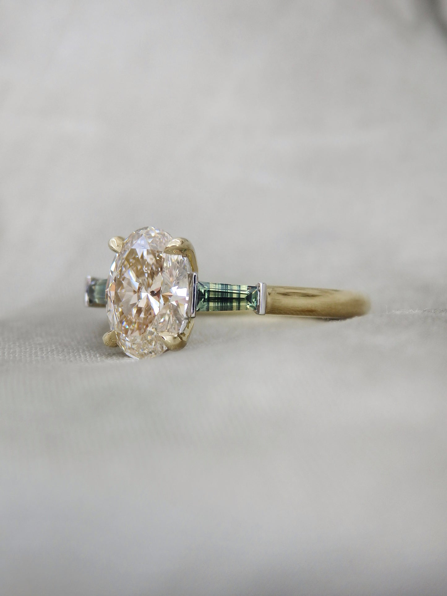 natural oval diamond held in 4 claws with striped colour zoned natural Australian sapphires held in platinum bar settings 