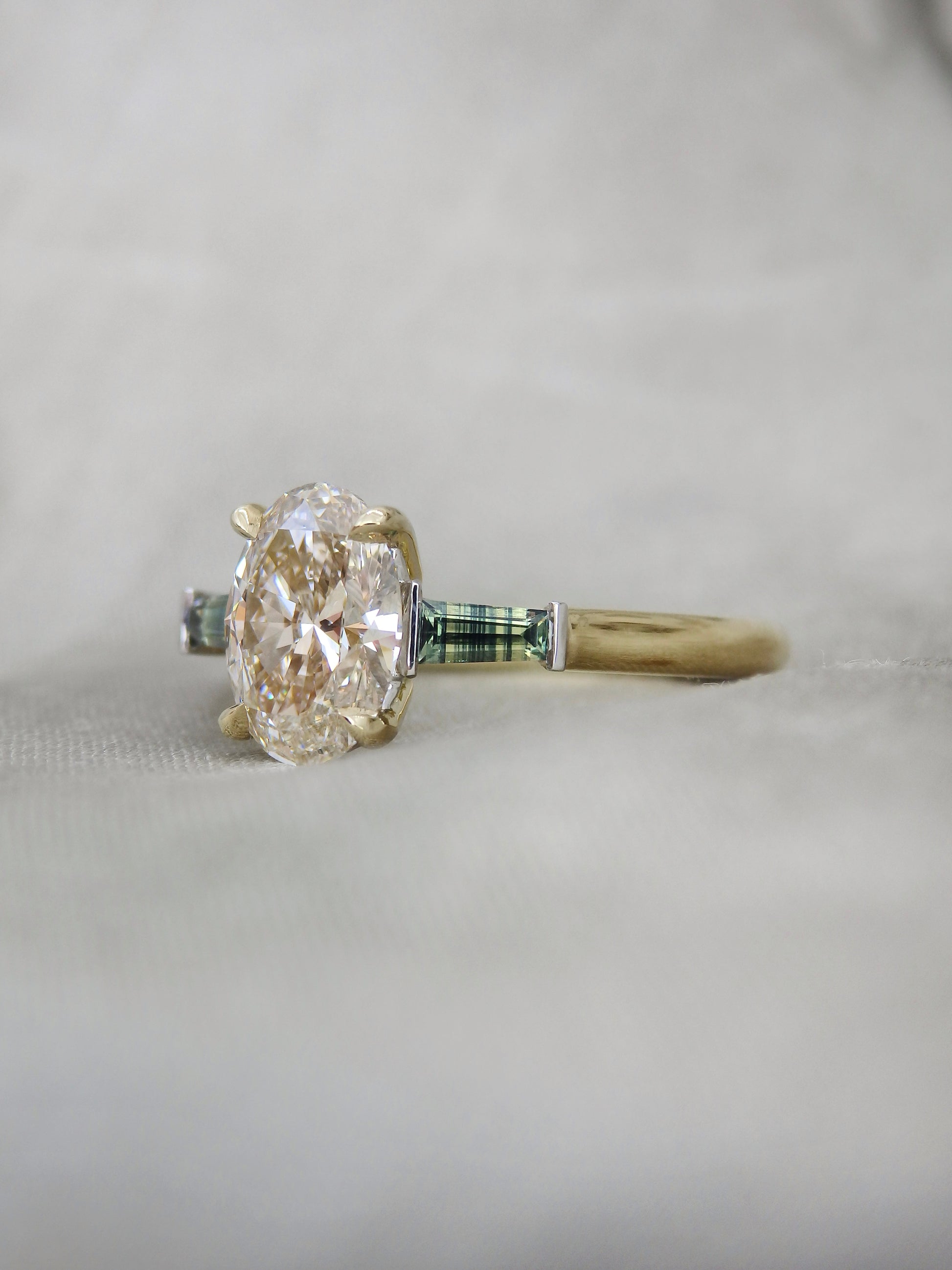 natural oval diamond held in 4 claws with striped colour zoned natural Australian sapphires held in platinum bar settings 