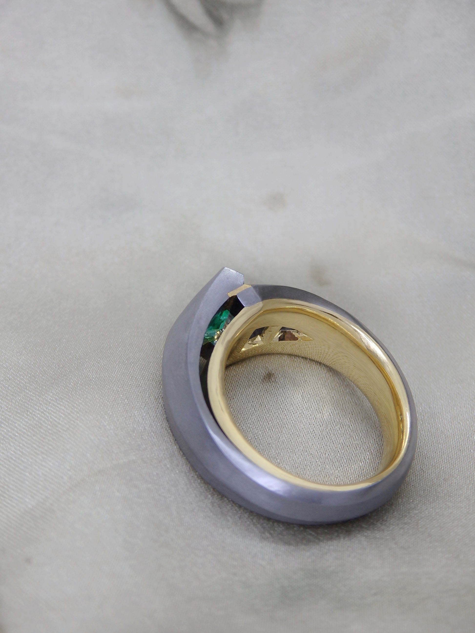 Australian Award-winning ring Caiman. A tantalum unisex engagement or dress ring with 18ct and 22ct yellow gold details with a geometric shield cut bright green Colombian Emerald and tapering sort deco step cut trapezoidal and bullet cut natural diamonds, an engineered ring with negative spaces and fine details