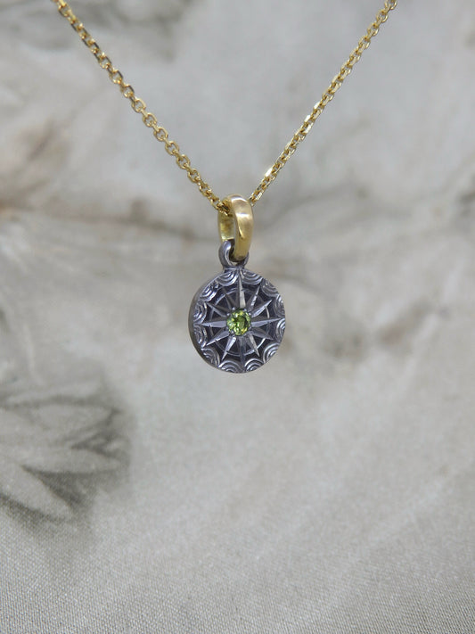 Australian sapphire pendant in hand-engraved pure tantalum with an 18ct yellow gold chain loop. The sapphire is set in a 12-pointed star with a ring around it, each point separated by an engraved ripple around the outside. 